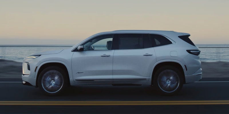 White Buick Enclave SUV driving along a coastal road