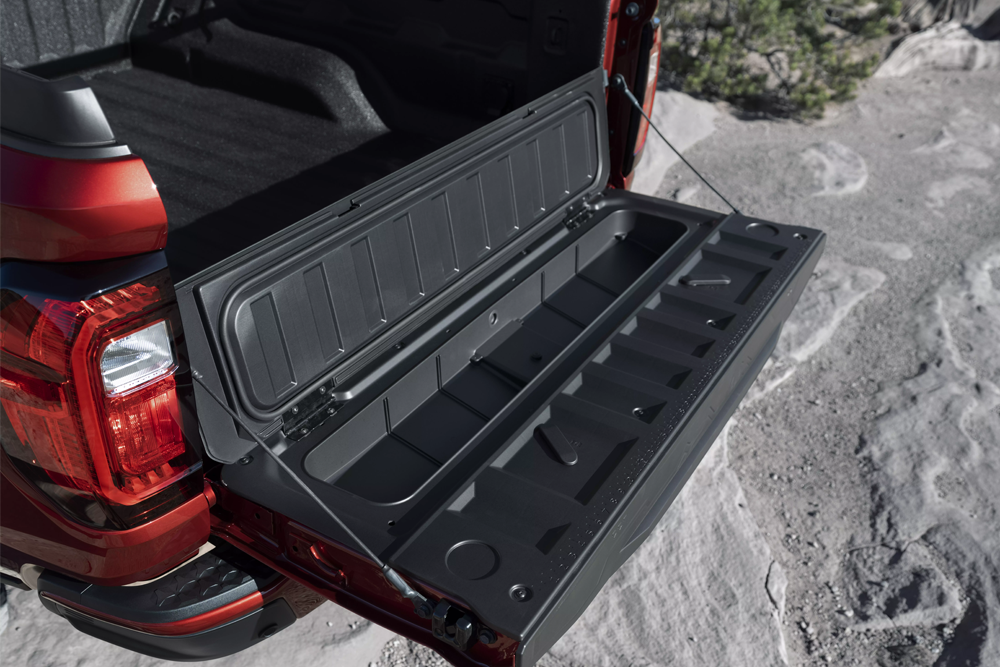 Red GMC Canyon tailgate lowered, revealing a hidden storage compartment and integrated step.