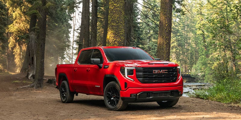 Red GMC Sierra 1500 parked on a forest trail
